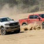 Two Ford trucks, a white 2021 Ford Ranger Tremor XLT and a red 2021 Ford Ranger Tremor Lariat are racing through the sand.