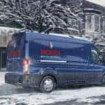 A blue 2020 Ford Transit Cargo is driving over a snowy road.