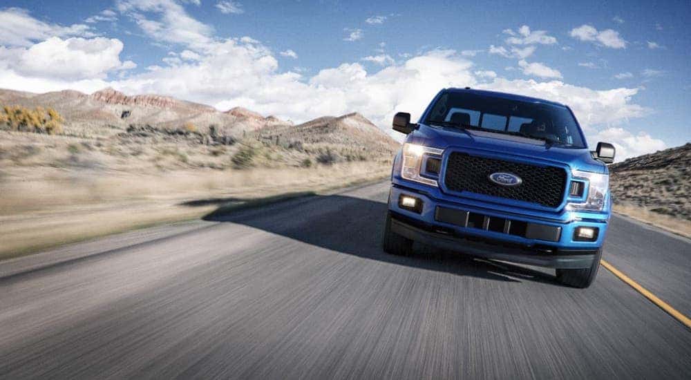A blue 2018 Ford F-150 diesel is shown from the front driving on a highway.