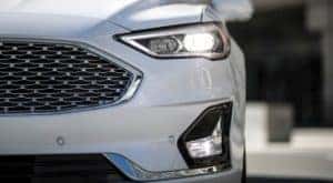 A closeup shows the grille of a white 2020 Ford Fusion at an Albany car dealer.