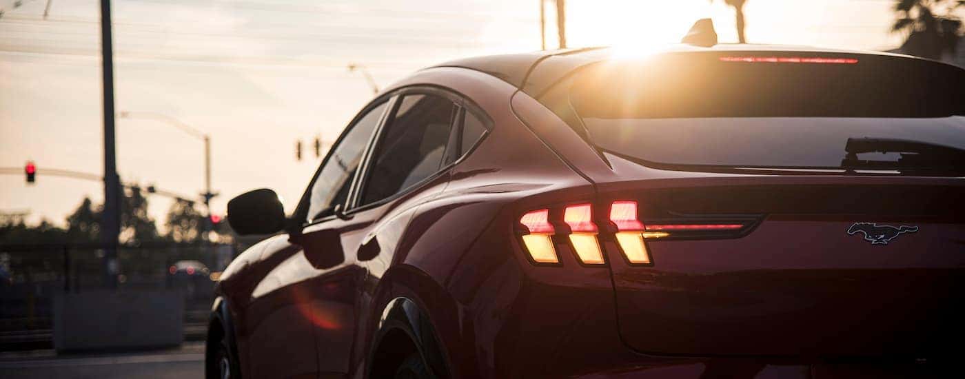 A close up shows the driver side taillight on a red 2021 Ford Mustang Mach-E during sunset.