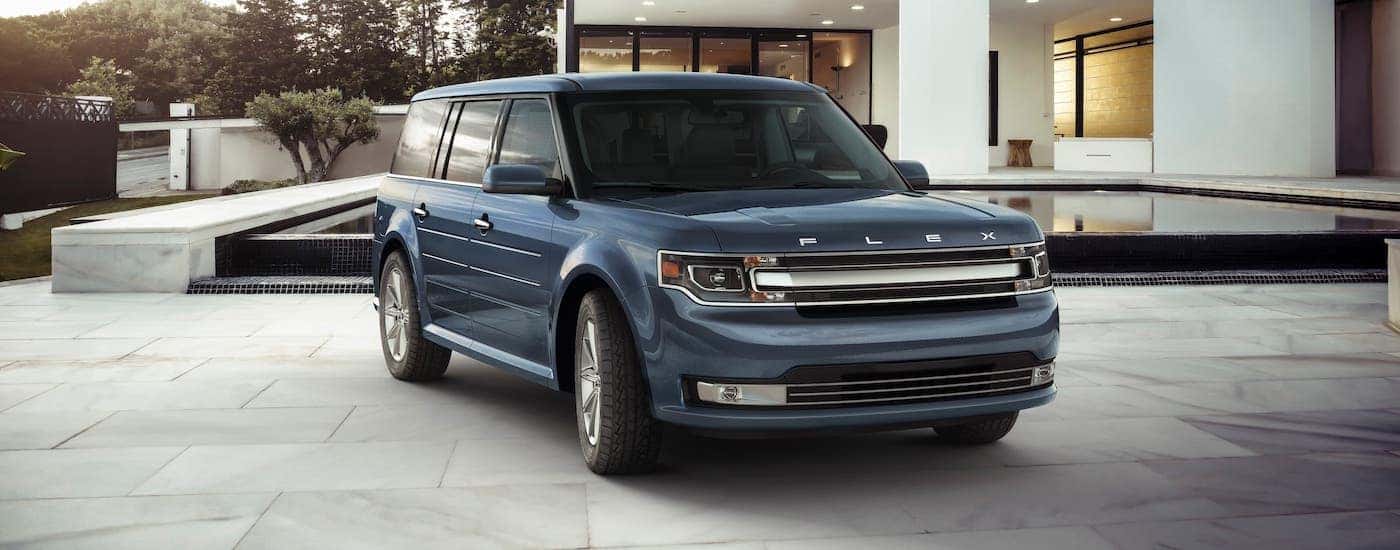 A blue 2017 Ford Flex is parked in front of a modern home.