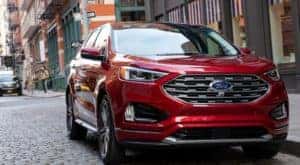 A red 2019 Ford Edge from a used Ford dealership is parked on a cobblestone city street.