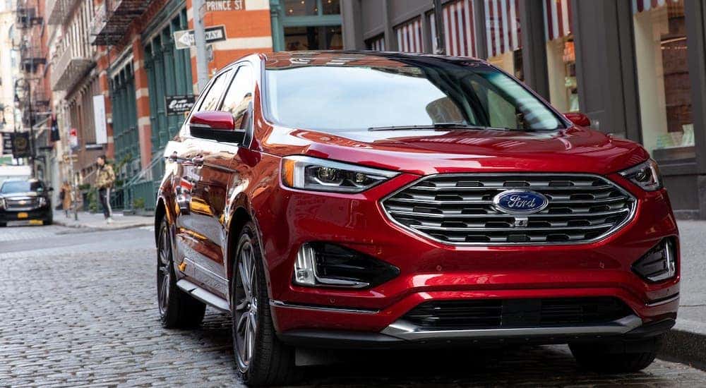 A red 2019 Ford Edge from a used Ford dealership is parked on a cobblestone city street.
