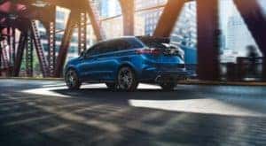 A blue 2020 Ford Edge is driving under a bridge after leaving a Capital Region used car dealer.