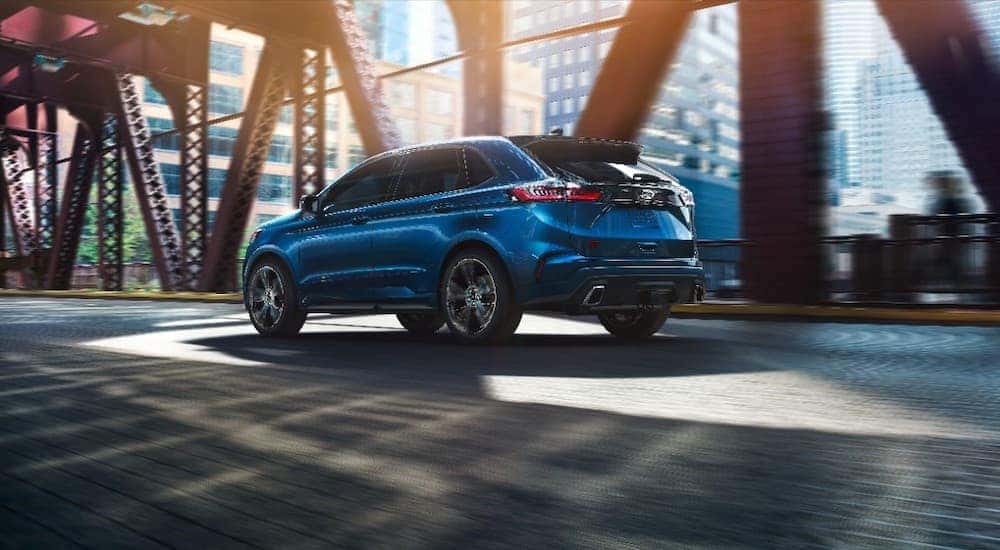 A blue 2020 Ford Edge is driving under a bridge after leaving a Capital Region used car dealer.