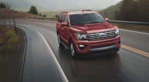 A red 2021 Ford Expedition is driving on a winding highway.