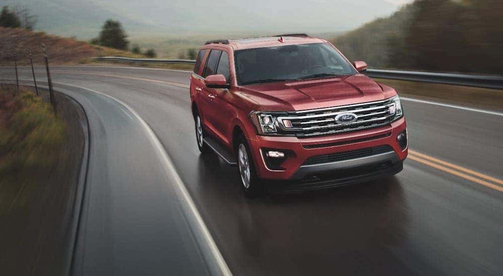 A red 2021 Ford Expedition is driving on a winding highway.