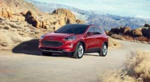 A red 2020 Ford Escape is driving on a desert highway.