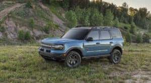 A blue 2021 Bronco Sport from a Ford Bronco Sport dealer is parked on a grassy mountain.