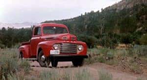 A red 1948 Ford F Series is shown parked on a dirt path.