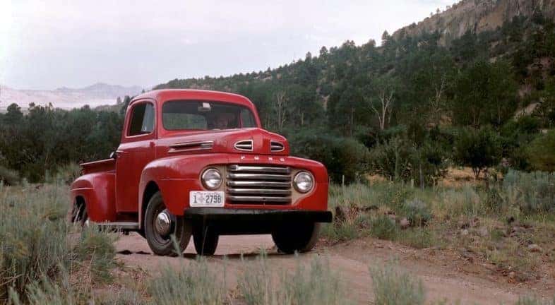 A red 1948 Ford F Series is shown parked on a dirt path.
