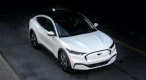 A white 2021 Ford Mustang Mach-E is shown from a high angle after leaving a Ford electric car dealership.