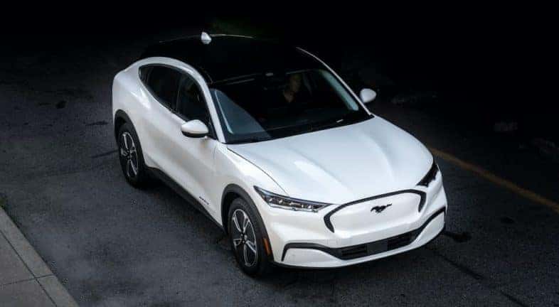 A white 2021 Ford Mustang Mach-E is shown from a high angle after leaving a Ford electric car dealership.