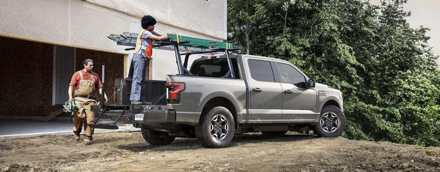A grey 2023 Ford F-150 Lightning is shown on a construction site.