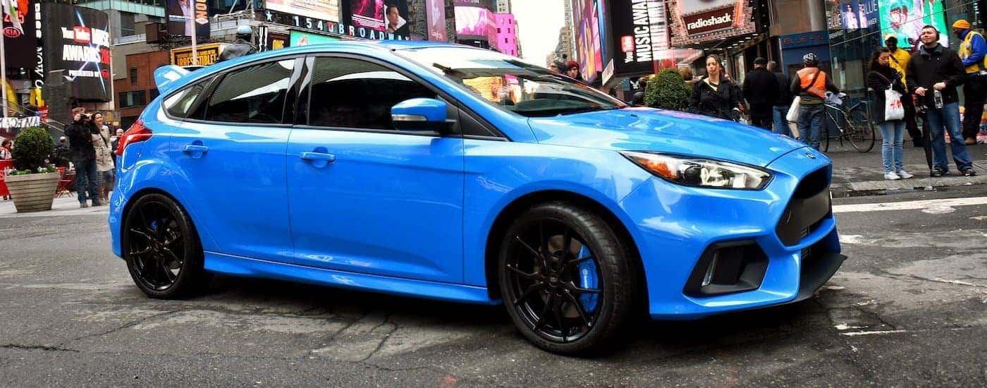 A blue 2016 Ford Focus RS is shown from the side parked in Times Square.