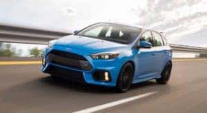 A blue 2016 Ford Focus RS is driving on a highway after leaving a used Ford Focus dealer.