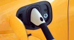 A close up shows a cable charging a yellow 2021 Ford Mustang Mach-E GT.