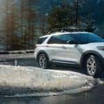 A white 2021 Ford Explorer is shown driving around a curve after leaving a Ford Explorer ST dealer.