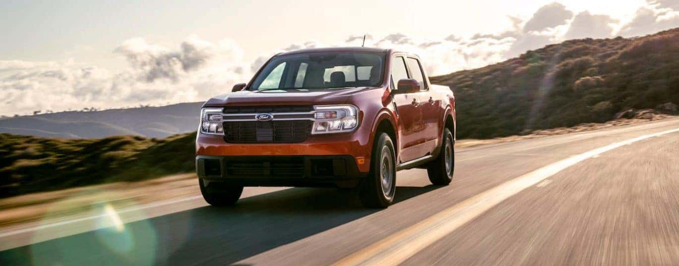 A red 2022 Ford Maverick Lariat is shown driving on a sunny day after being in the 2022 Ford Maverick vs 2021 Ford Ranger comparison.