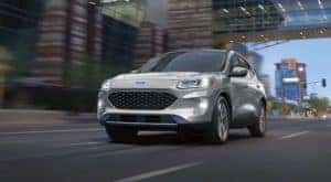 A white 2020 Ford Escape Hybrid Titanium is shown driving through a city.