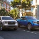A silver and a blue 2022 Ford Maverick are shown on a city street.