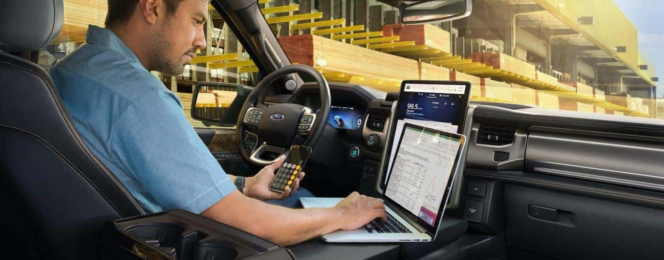 A person is shown using a laptop in a 2022 Ford F-150 Lightning Lariat.