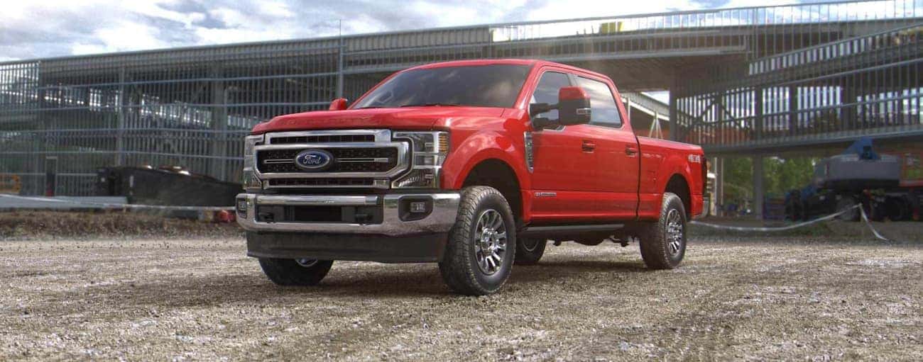 A red 2022 Ford F-250 is shown from the front parked in front of a barn.