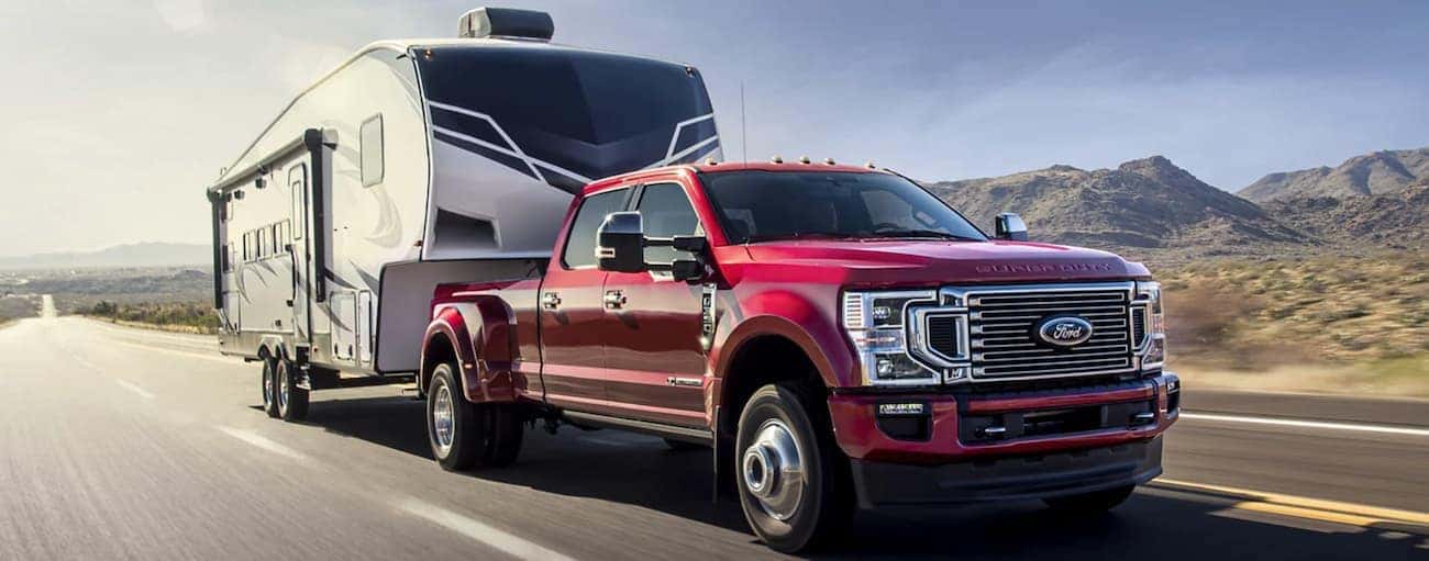 A red 2022 Ford F-350 is shown towing a trailer down an open highway after winning a 2022 Ford F-350 vs 2022 Chevy Silverado 3500 HD comparison.