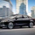 A black 2017 Ford Fusion Energi is shown communting through a city.