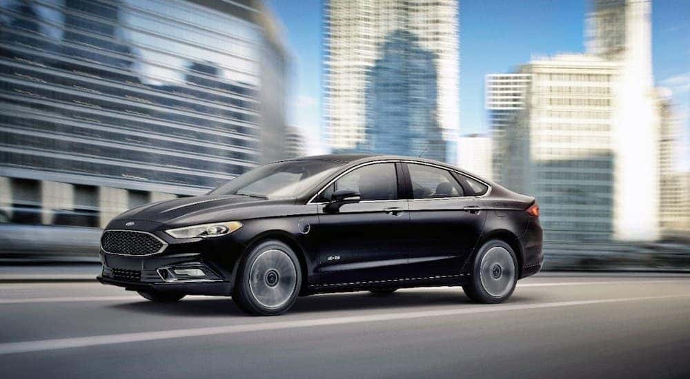 A black 2017 Ford Fusion Energi is shown communting through a city.