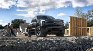 A black 2022 Ford F-150 Lightning Pro is shown on a construction site.