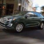 A black 2016 Ford Edge is shown driving on a city street.