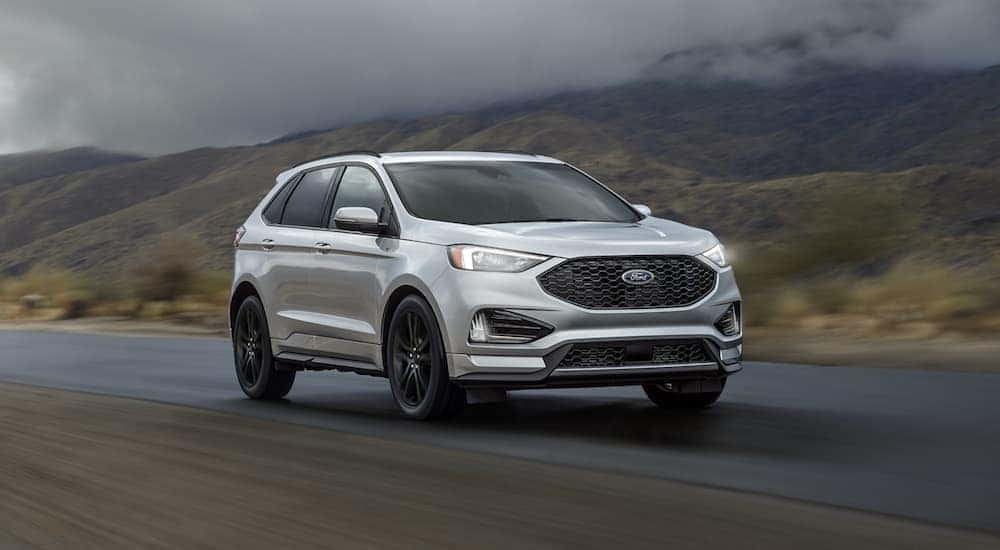 A silver 2019 Ford Edge is shown driving to an Albany used vehicle dealership on a foggy road.