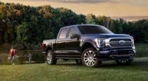 A blue 2021 Ford F-150 is shown from the front parked on a field.