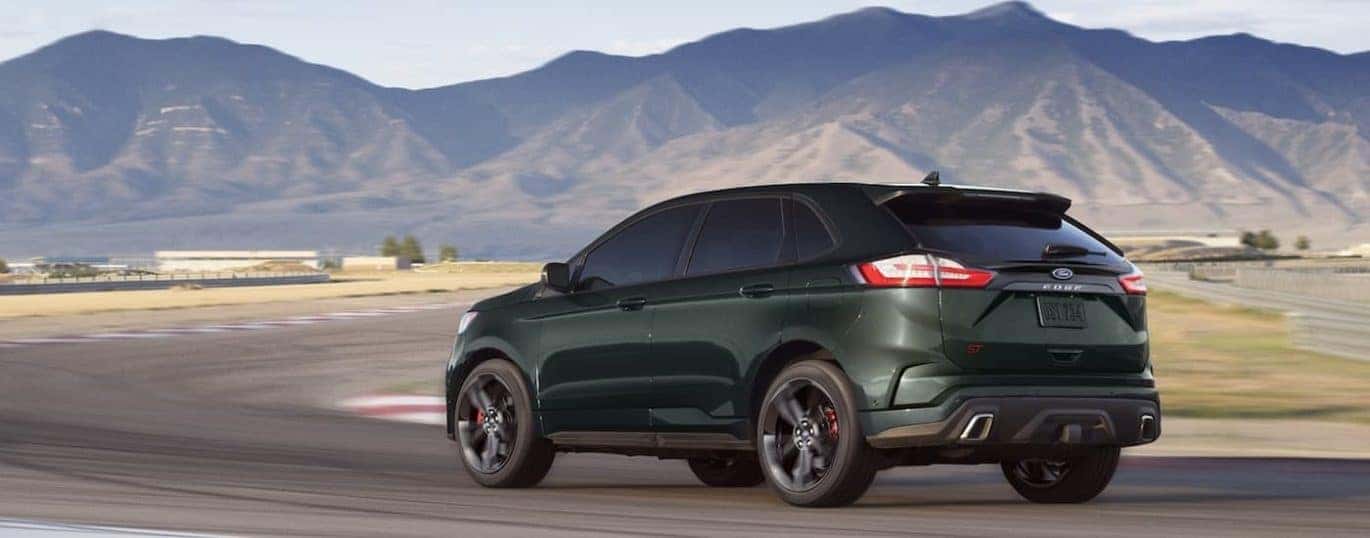 A green 2022 Ford Edge ST is shown from a rear angle driving on a track.