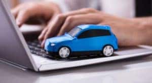 A close up shows a person searching "sell my car" on a laptop next to a blue toy car.