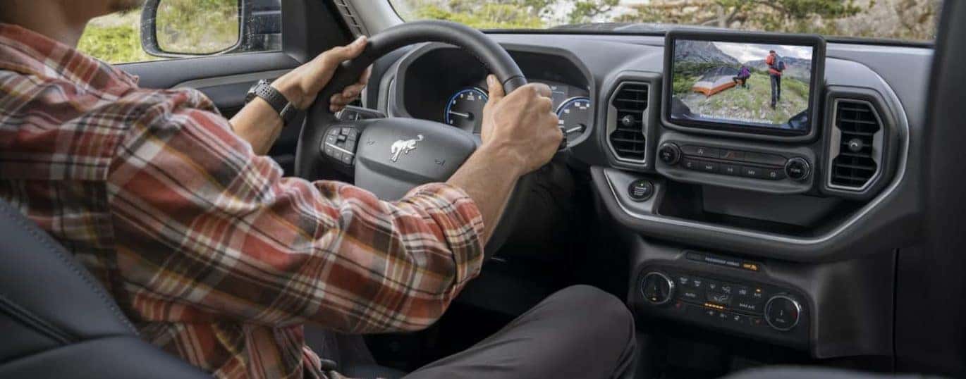The black interior of a 2022 Ford Bronco Sport shows the steering wheel and infotainment screen.