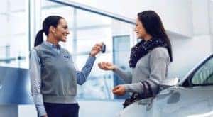 A customer is shown speaking to a saleswoman at a certified pre-owned Ford dealership.