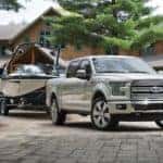 A white 2016 Ford F-150 Limited is shown with a boat in a driveway after visiting a Certified Pre-Owned Ford F-150 dealer.