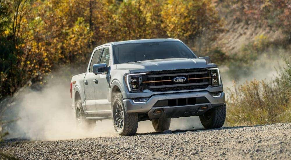A silver 2021 Ford F-150 Tremor is shown driving on a dusty path.
