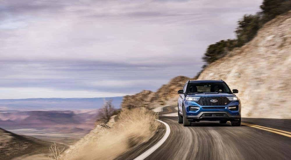 A dark blue 2020 Ford Explorer ST is shown driving on a winding road after visiting a Schenectady used Ford dealer.