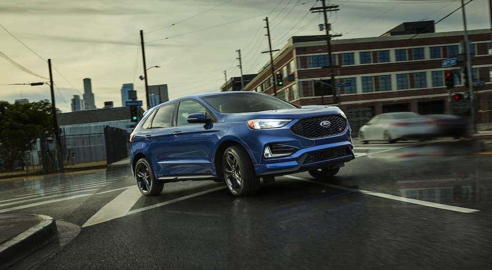 A blue 2018 Ford Edge is shown driving through an intersection.