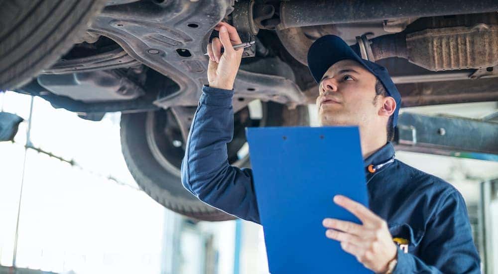 A mechanic is shown inspecting a Certified Pre-Owned car at a Certified Pre-Owned Ford dealership.