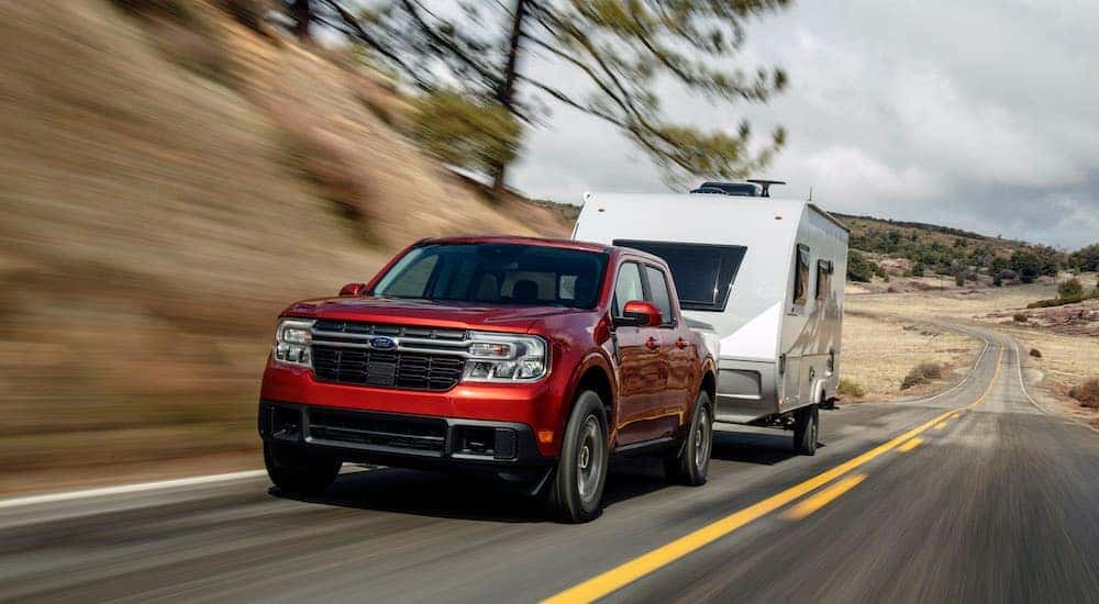 A red 2022 Ford Maverick Lariat is shown towing a camper after leaving a Schenectady Ford Dealer.