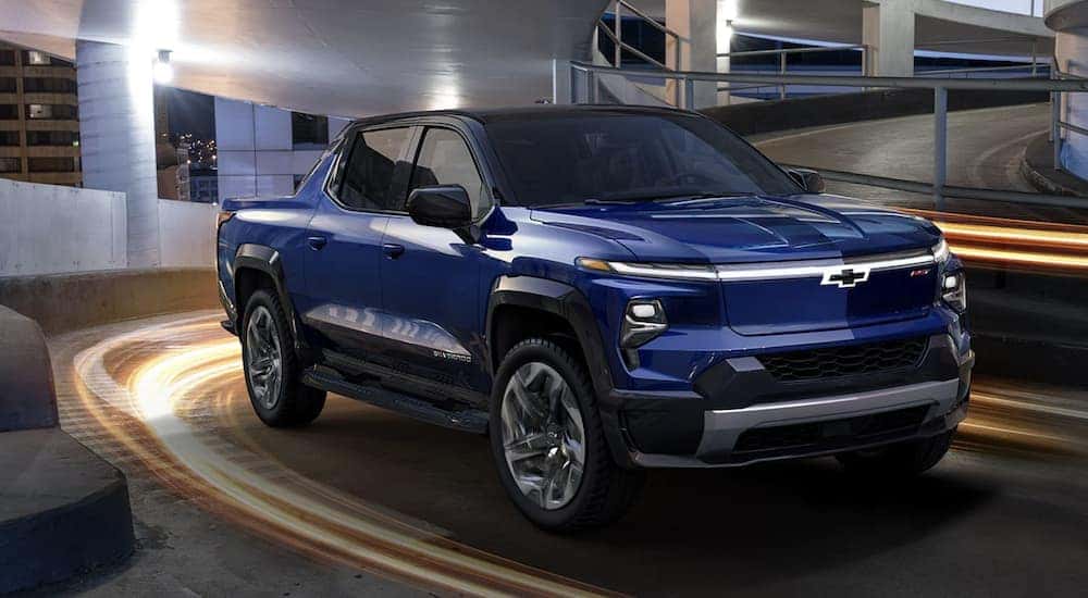 A blue 2024 Chevy Silverado EV is shown driving at night.