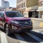 A maroon 2017 Ford Edge is shown from an angle driving through an intersection.