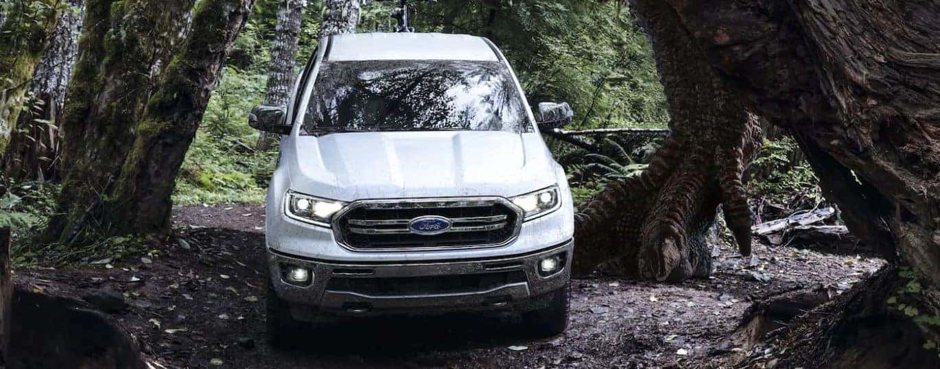 A white 2022 Ford Ranger Lariat is shown driving on a forest trail.