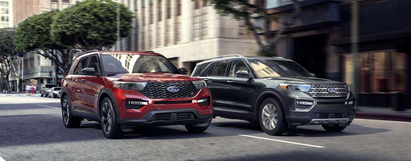 A red and grey 2020 Ford Explorers are shown driving side by side on a city.