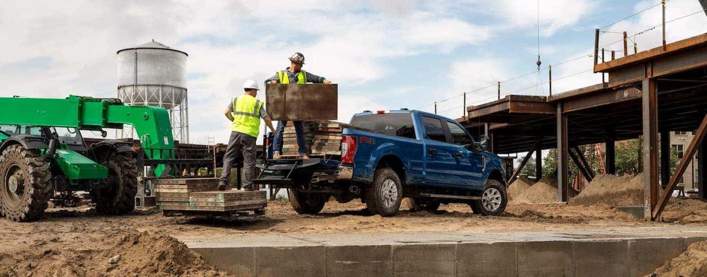 A popular used truck for sale, a blue 2020 Ford F-250 Super Duty, is shown from the side parked at a construction side.